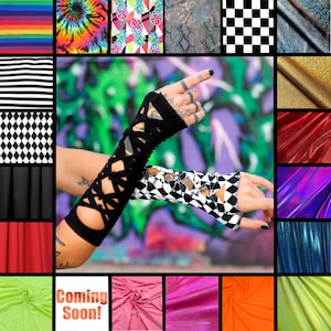 May include: A pair of arm warmers featuring a black solid fabric with a crisscross lace-up design on one arm and a black and white diamond pattern with a similar lace-up detail on the other, displayed against a colourful graffiti background.