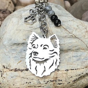 Könnte beinhalten: Silberner Schlüsselanhänger mit einer Hundesilhouette, einem Pfotenanhänger und schwarzen Perlen.