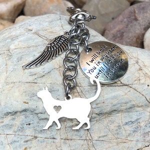 May include: Silver keychain featuring a cat silhouette, a small angel wing charm, and a round charm inscribed with the words "I will hold you in my heart until I hold you in heaven".