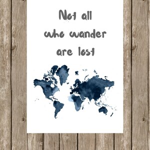May include: A white print with the text "Not all who wander are lost" in gray lettering above a watercolor map of the world in shades of blue. The print is displayed against a wooden background.
