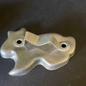 May include: A silver metal cookie cutter shaped like a ghost. The cutter has a handle on the back.
