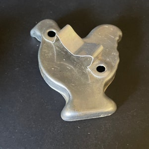 May include: A vintage metal cookie cutter shaped like a turkey. The cutter has two holes on the side and a metal handle.