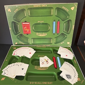 May include: A Tripoley board game set featuring a green plastic tray with designated slots for cards and chips. The board includes text labels like Pot, Kitty, Ace, King, Queen, Jack, and 8-9-10 All One Suit. Includes playing cards and game chips.