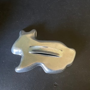 May include: A silver metal cookie cutter shaped like a rabbit. The cutter has a handle on the back.