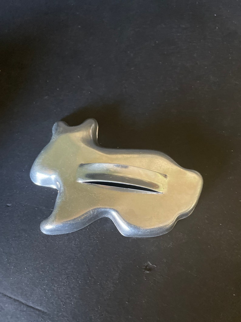 May include: A silver metal cookie cutter shaped like a rabbit. The cutter has a handle on the back.