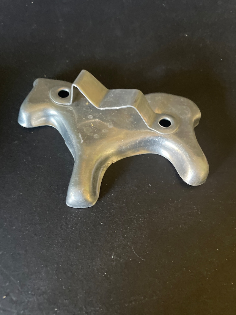 May include: A silver metal cookie cutter shaped like a horse. The cutter has two holes on the top for hanging.