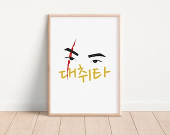 May include: A white framed print with a black and red illustration of an eye with a scar and the Korean text "대추타" in gold.