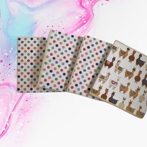 May include: Four notebooks with different patterns. One notebook has a white background with colourful polka dots. Another notebook has a white background with a pattern of llamas. The other two notebooks have a white background with colourful polka dots.