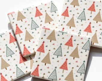 Peut inclure: Un ensemble de quatre dessous de verre carrés en céramique arborant un motif répétitif de sapins de Noël stylisés dans des tons rose, beige et bleu sarcelle sur fond blanc, agrémenté de petites étoiles dispersées sur tout le design.