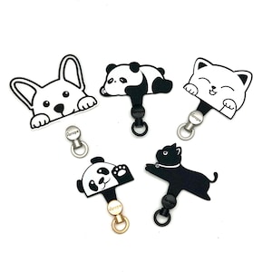 May include: A collection of black and white animal-shaped charms, including a corgi, panda, and cat. Each charm has a metal ring and a small tag with the word "Europe" on it. The charms are on a white background.