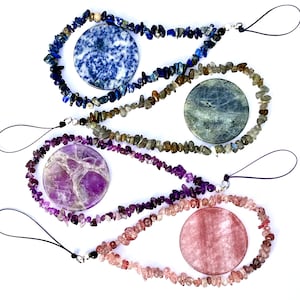 May include: Three phone charms made with chip stone beads and a round stone charm. The charms are in shades of blue, purple, and pink.