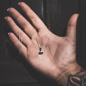 May include: A silver chain necklace with a small silver hammer pendant.