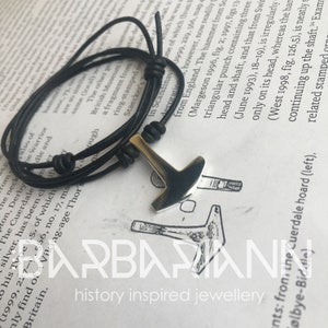 May include: A silver Mjolnir pendant on a black leather cord bracelet. The pendant is a replica of the Norse god Thor's hammer.