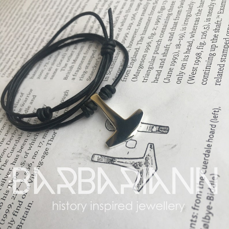 May include: A silver Mjolnir pendant on a black leather cord bracelet. The pendant is a replica of the Norse god Thor's hammer.