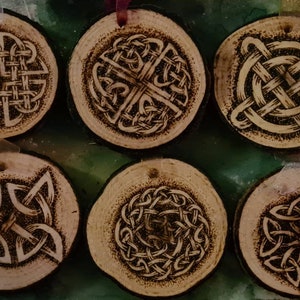 May include: Six wooden ornaments featuring Celtic knot designs burned into the surface. The ornaments are round and have a natural wood finish.