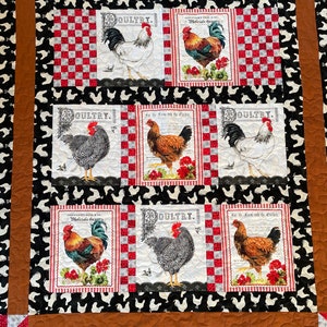 May include: A quilt with a black background and white rooster silhouettes. The quilt is made up of squares with red and white checkered patterns. Each square contains a vintage-style illustration of a rooster with the word "Poultry" printed on it. The illustrations feature different breeds of roosters, including a white rooster, a black and white rooster, and a brown rooster.