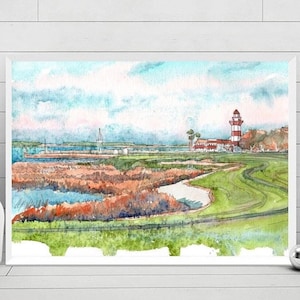 May include: Watercolor painting of a coastal landscape featuring a lighthouse with red and white stripes. The artwork depicts a green golf course, marshland, and a cloudy blue sky. The painting is framed and displayed on a white surface.