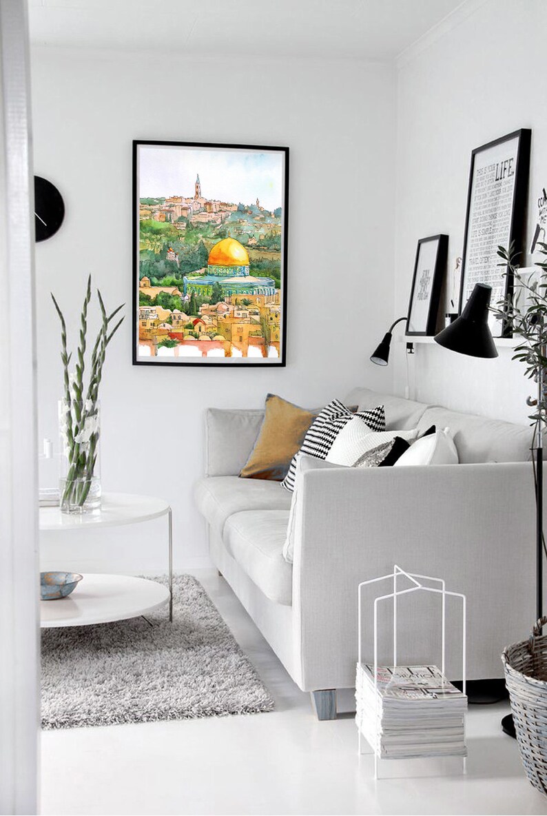 Peut inclure: Une peinture &agrave; l'aquarelle du D&ocirc;me du Rocher &agrave; J&eacute;rusalem, encadr&eacute;e et accroch&eacute;e &agrave; un mur blanc dans un salon. La peinture est au-dessus d'un canap&eacute; blanc avec des coussins et une table basse blanche.