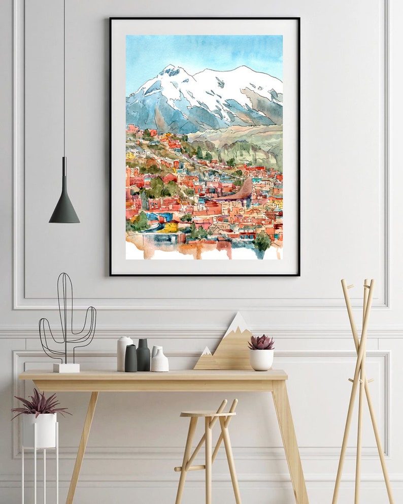 Pu&ograve; includere: Un dipinto ad acquerello di una citt&agrave; incastonata in una valle di montagna. La citt&agrave; &egrave; dipinta in tonalit&agrave; di rosso, arancione e giallo, con una montagna innevata sullo sfondo. Il cielo &egrave; azzurro chiaro con nuvole bianche.