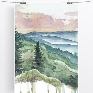 May include: Watercolor painting of a mountain landscape with a pink and orange sunset sky. The mountains are covered in green trees and there is a layer of fog in the valleys.