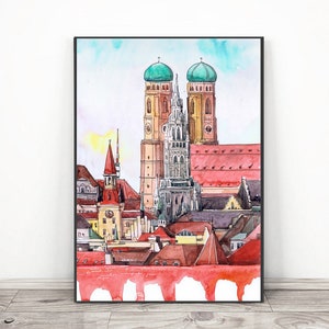 Peut inclure: Peinture à l'aquarelle d'un paysage urbain avec de grands bâtiments aux toits rouges et des tours à dômes verts. L'œuvre est encadrée d'un bord noir et se détache sur un ciel bleu clair. La peinture est exposée sur un mur blanc.