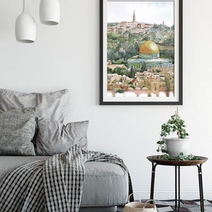 Peut inclure: Une peinture &agrave; l'aquarelle du D&ocirc;me du Rocher &agrave; J&eacute;rusalem, un d&ocirc;me dor&eacute; avec un toit vert, entour&eacute; de b&acirc;timents et d'arbres. La peinture est encadr&eacute;e en noir et accroch&eacute;e &agrave; un mur blanc.