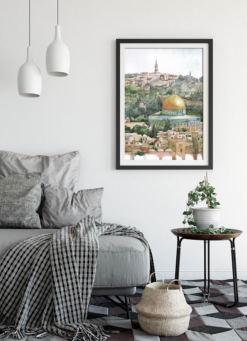 Peut inclure: Une peinture &agrave; l'aquarelle du D&ocirc;me du Rocher &agrave; J&eacute;rusalem, un d&ocirc;me dor&eacute; avec un toit vert, entour&eacute; de b&acirc;timents et d'arbres. La peinture est encadr&eacute;e en noir et accroch&eacute;e &agrave; un mur blanc.