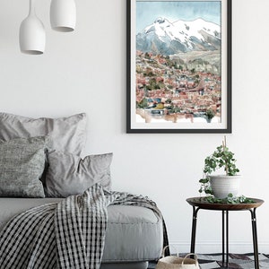 Pu&ograve; includere: Un dipinto ad acquerello di una citt&agrave; incastonata in una valle di montagna. La citt&agrave; &egrave; composta da edifici colorati con tetti rossi. La montagna &egrave; innevata e il cielo &egrave; azzurro chiaro.