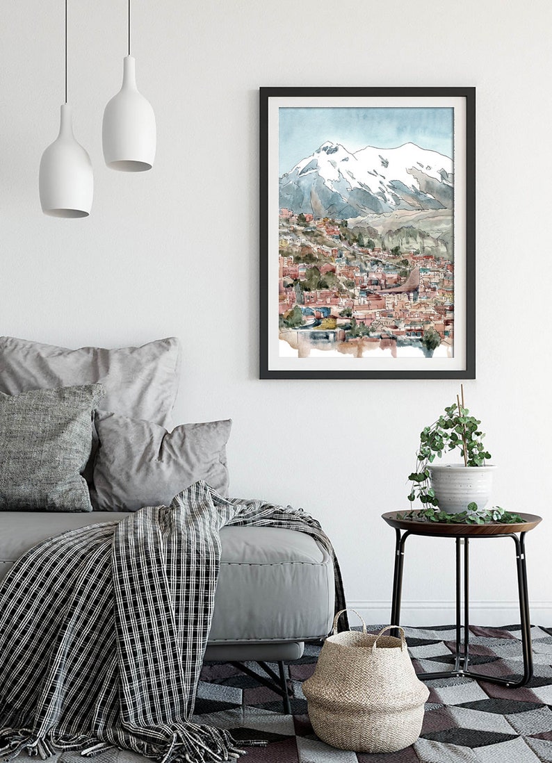 Pu&ograve; includere: Un dipinto ad acquerello di una citt&agrave; incastonata in una valle di montagna. La citt&agrave; &egrave; composta da edifici colorati con tetti rossi. La montagna &egrave; innevata e il cielo &egrave; azzurro chiaro.
