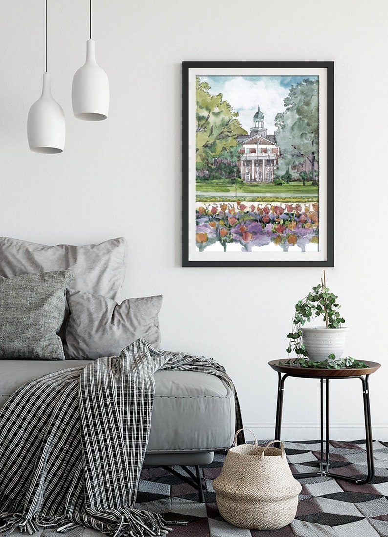 K&ouml;nnte beinhalten: Ein Aquarellbild eines Geb&auml;udes mit einer wei&szlig;en Fassade und einem gr&uuml;nen Dach. Das Geb&auml;ude ist von B&auml;umen und Blumen umgeben. Das Bild ist in Schwarz gerahmt und h&auml;ngt an einer wei&szlig;en Wand.