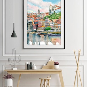 K&ouml;nnte beinhalten: Aquarellgem&auml;lde einer Stadtlandschaft mit bunten Geb&auml;uden und einem Fluss im Vordergrund. Die Geb&auml;ude sind dicht beieinander und haben verschiedene Architekturstile. Der Fluss ist ruhig und spiegelt den Himmel und die Geb&auml;ude wider.