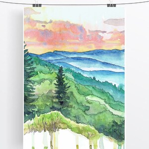 May include: Watercolor painting of a mountain landscape with a sunset sky. The painting features a series of blue mountains with a green forest in the foreground. The sky is a mix of pink, orange, and yellow.