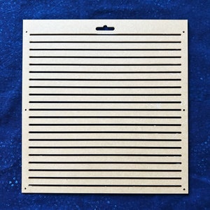 Puede incluir: Un panel de madera marrón claro con una serie de ranuras horizontales espaciadas uniformemente cortadas. El panel tiene un pequeño agujero en la parte superior para colgarlo.