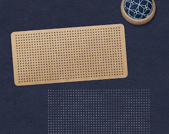 May include: A brown pegboard with a grid of evenly spaced holes. A blue and white pincushion sits on a dark blue surface.