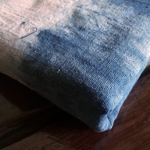 Puede incluir: Primer plano de un trozo de tela doblado con un patrón de tie-dye azul y blanco. La tela es texturizada y tiene un tacto ligeramente áspero.