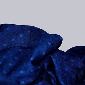May include: A blue fabric with a white polka dot pattern. The fabric is folded and draped, creating a soft and textured look.