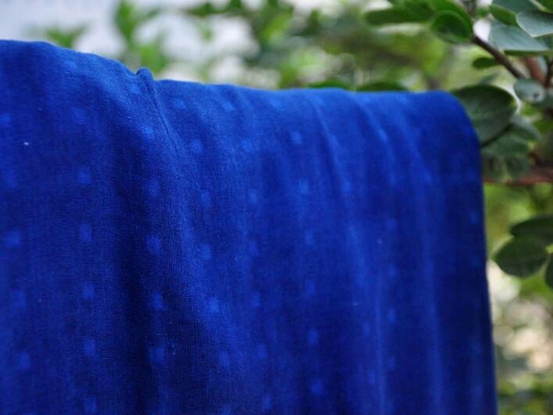 May include: A close-up of a blue fabric with a white pattern. The fabric has a soft, textured feel and is perfect for crafting or sewing projects.
