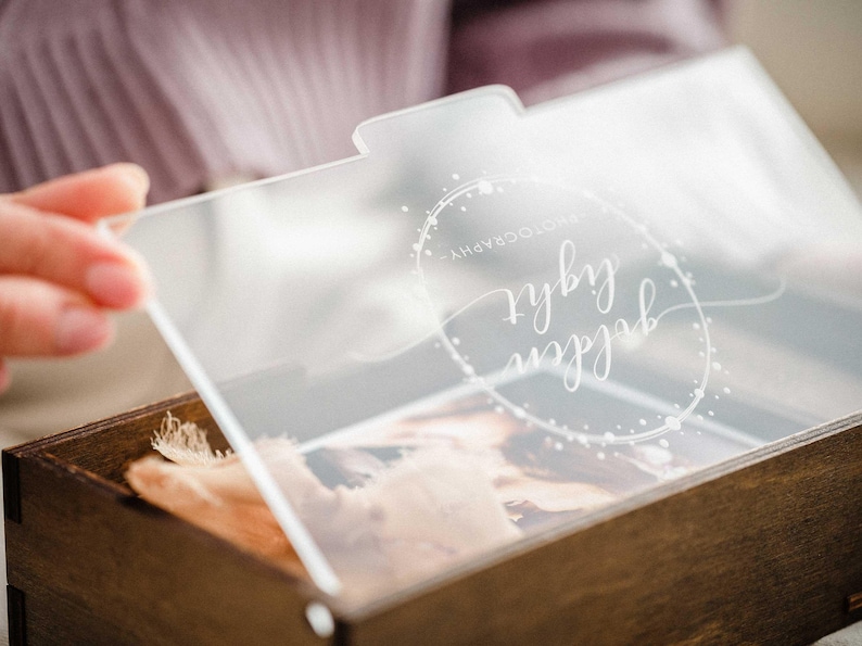 Close-up of engraved clear acrylic lid on walnut photo box, personalized name/date example.