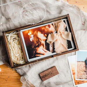 pen wooden photo box with 4x6 prints, ribbon and wood shavings, showing gift-ready presentation.