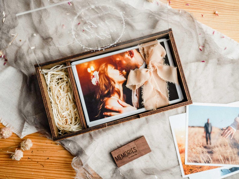 pen wooden photo box with 4x6 prints, ribbon and wood shavings, showing gift-ready presentation.