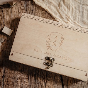 May include: A wooden box with a hinged lid and a metal latch. The box is engraved with the initials "A & N" and the text "MR. & MRS. ESCALERA".
