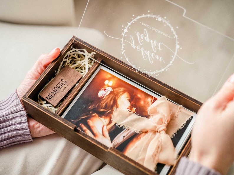 Open wooden photo box on lap showing 4x6 photo storage and separate USB compartment.