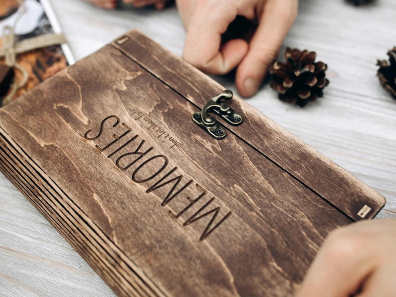 May include: A dark brown wooden box with a latch and the word "MEMORIES" engraved on the front. The box is made of layered wood and has a rustic look.