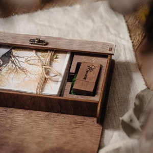 May include: A wooden box with a hinged lid, containing a stack of photographs and a small wooden USB drive engraved with the word "Memories".
