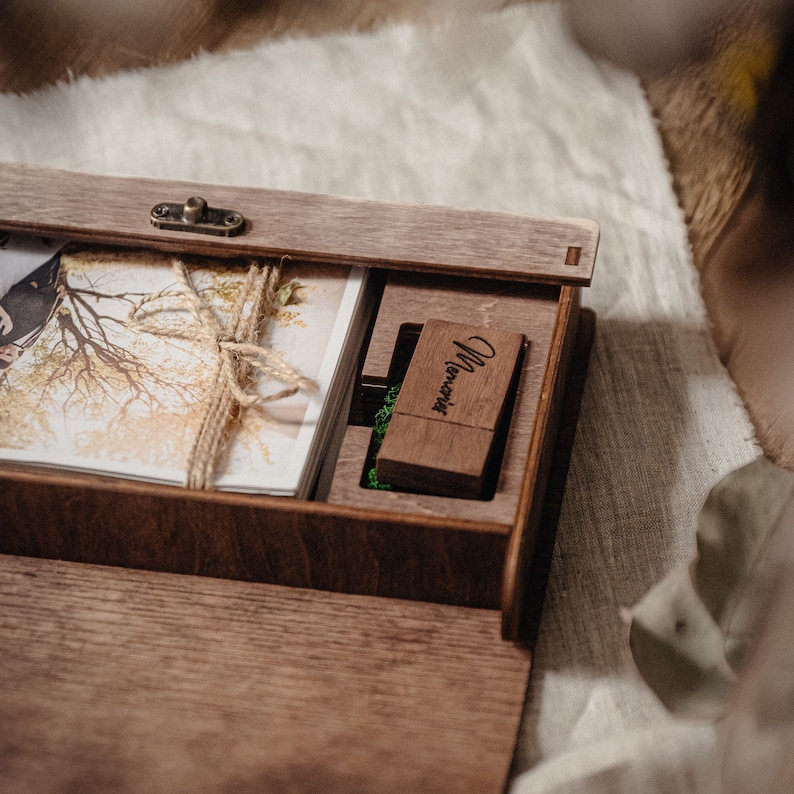 May include: A wooden box with a hinged lid, containing a stack of photographs and a small wooden USB drive engraved with the word "Memories".