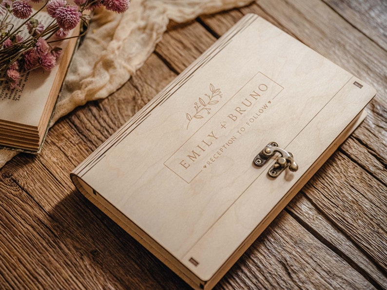 May include: A wooden box with a latch closure. The box is engraved with the text "Emily + Bruno" and "Reception to follow".