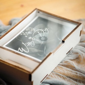 Close-up of white photo box with personalized acrylic lid engraving, minimal modern look.