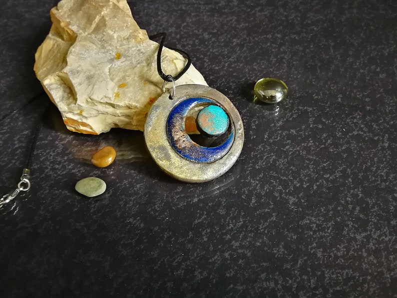 Ciondolo in ceramica Raku con tripla luna, simbolo wiccan minimalista, collana artigianale regolabile.
Raku ceramic pendant with triple moon, minimalist Wiccan symbol, adjustable handcrafted necklace.