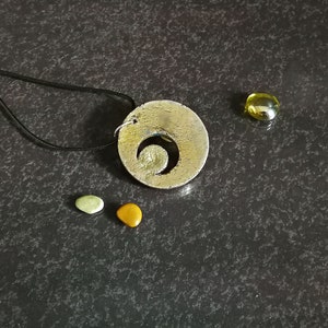 Ciondolo con fasi lunari in ceramica Raku, stile boho minimalista, decorato con colori iridescenti.
Raku ceramic moon phase pendant, minimalist boho style, decorated with iridescent colors.