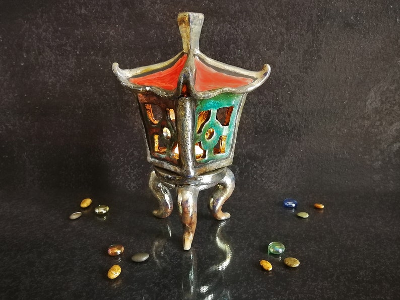 Lanterna per tealight Oki Gata in ceramica raku turchese con tetto rosso e treppiede dorato, colori personalizzabili.
Oki Gata Tealight Lantern in Turquoise Raku Ceramic with Red Roof and Golden Tripod, Customizable Colors.